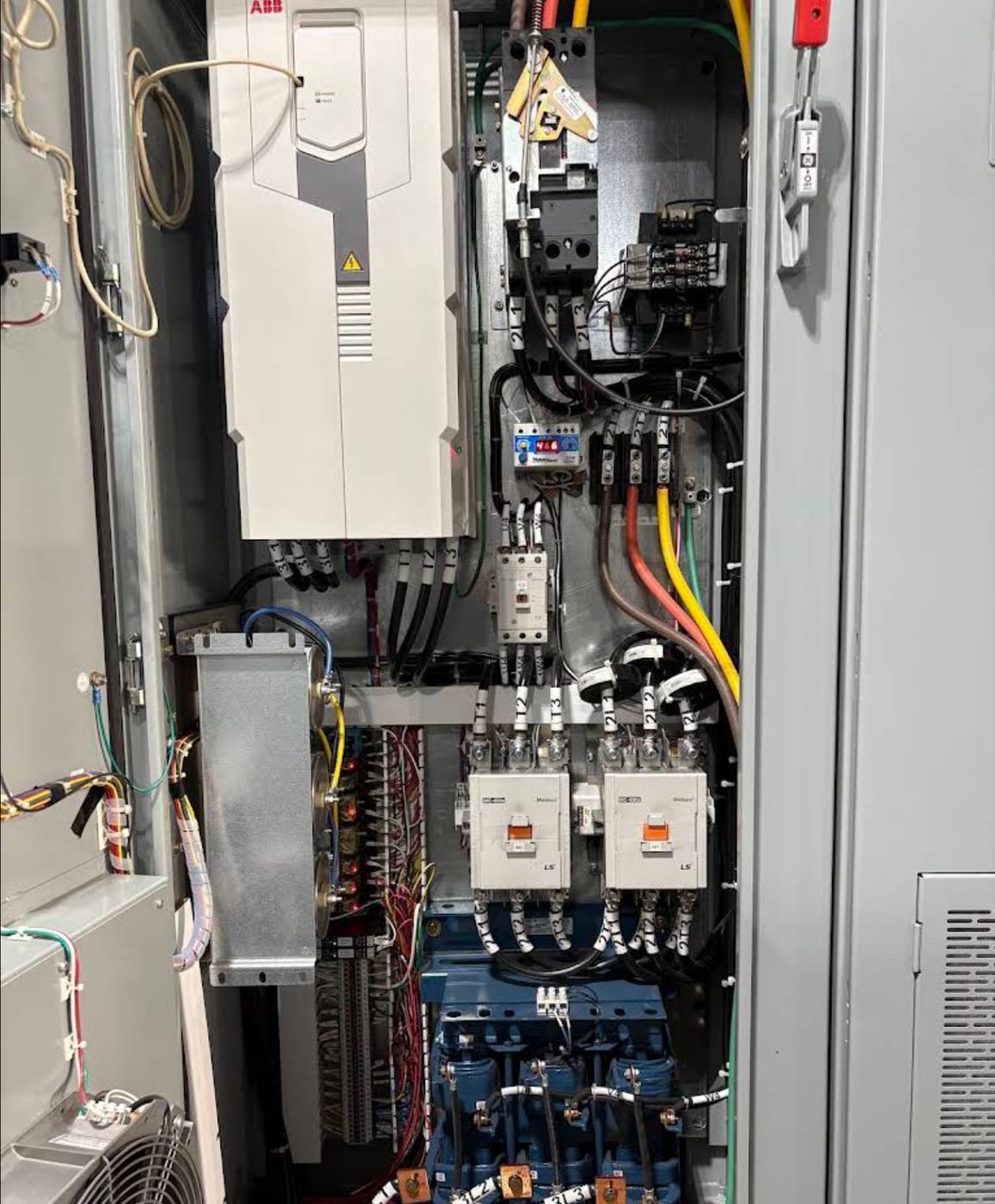 Open industrial control panel showing a variable frequency drive, contactors, terminal blocks and relays